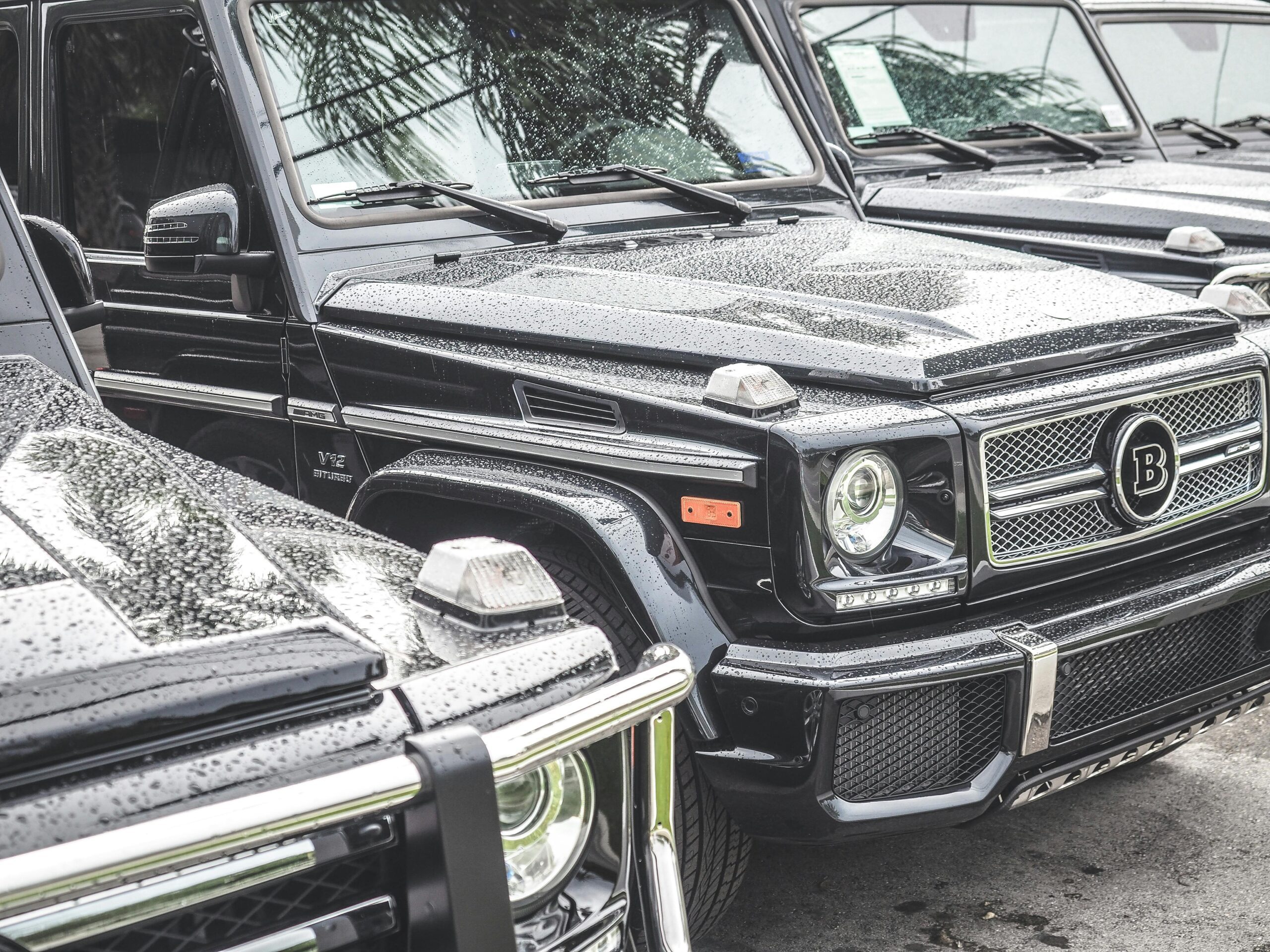 Close-up of luxurious black SUVs with raindrops, showcasing luxury vehicles under rainy conditions.