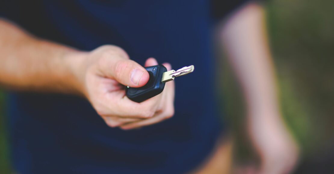 A hand holding a car key outdoors, emphasizing security and control.
