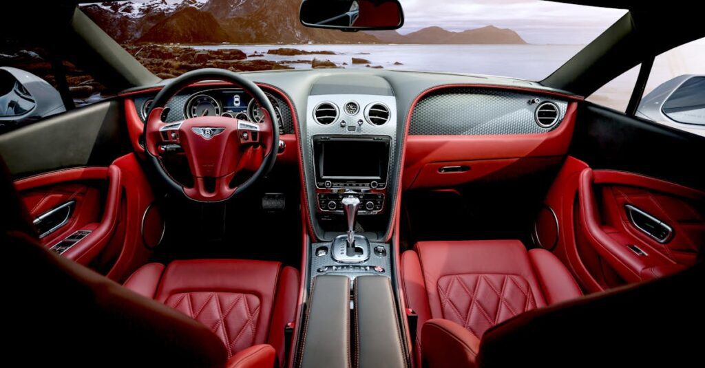 Red leather luxury sports car interior with mountain backdrop outside the window.