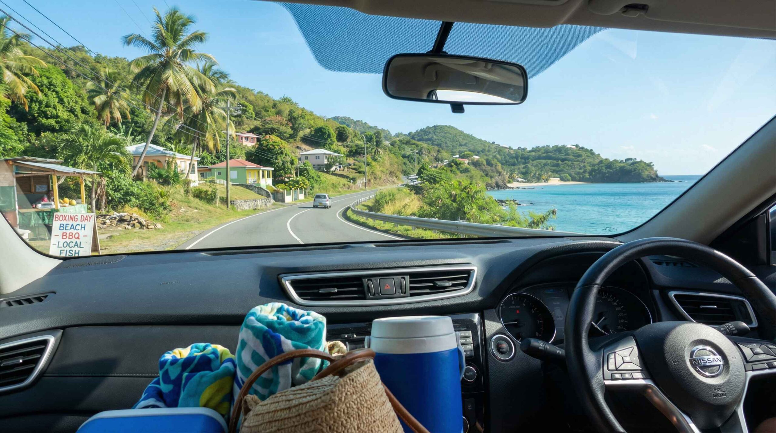 Boxing Day in Grenada with a rental car driving along a quiet coastal road, carrying beach gear and offering flexibility to explore multiple locations.