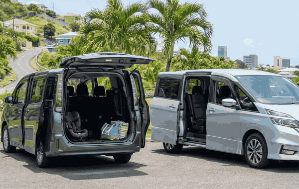 Toyota Noah and Nissan Serena minivans parked outdoors with sliding doors open, showing spacious interiors suitable for family or group travel.